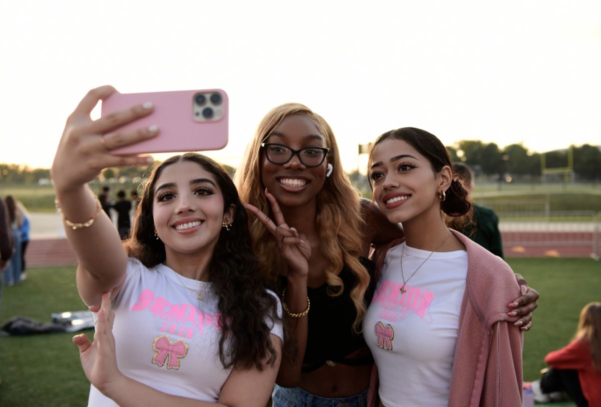 Smiling beside the sunrise, seniors Mercades Cisneros, Layla Davis and Samantha De La Torre Menjivar gather together to take a selfie. With a few clicks, the three had perfectly documented themselves and the cold, dewy morning on the SM South football field during the class of 25 senior sunrise on Aug. 24. 